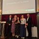 Members of the CEE team stand on stage at the AGCAS awards ceremony, holding a certificate. Behind them is a large screen displaying “University of Sussex Supporting Student/Graduate Employability Award AGCAS winner”