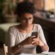 A woman looks at her phone with a concerned expression